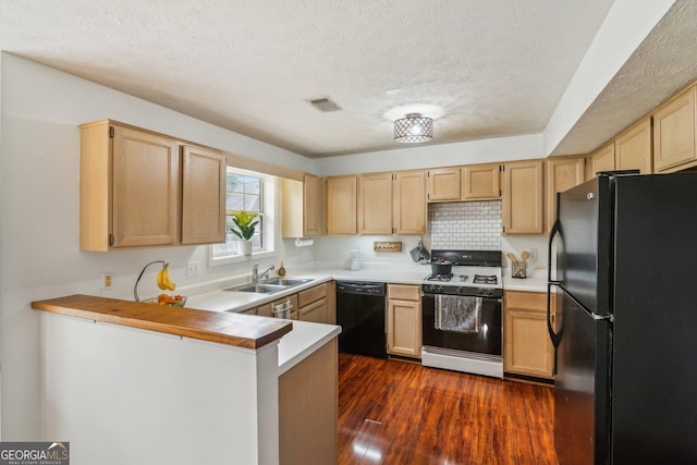 kitchen featuring visible vents, light brown cabinetry, a peninsula, black appliances, and a sink