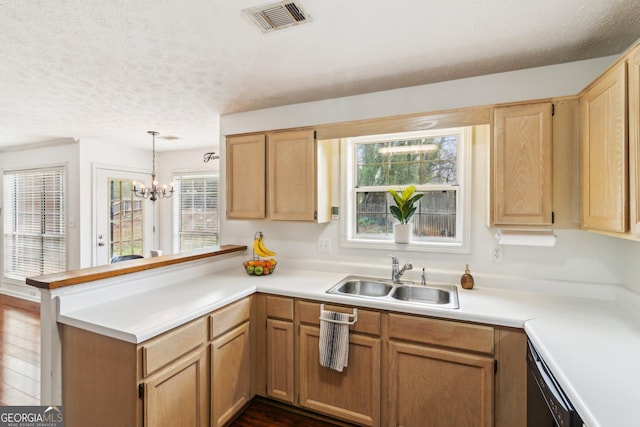 kitchen featuring a peninsula, light countertops, visible vents, and a sink