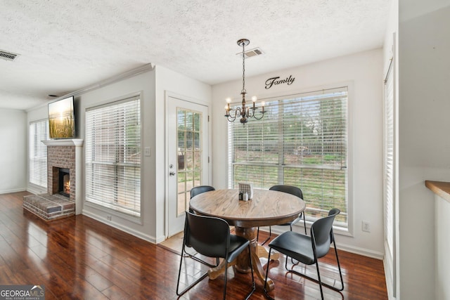 dining room with visible vents, an inviting chandelier, a fireplace, and dark wood-style flooring