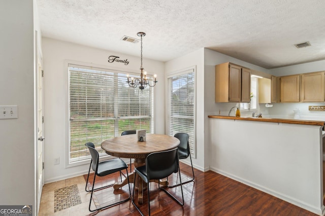 dining room featuring visible vents, wood finished floors, baseboards, and a chandelier