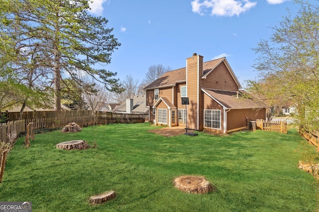 rear view of house with a yard, a fenced backyard, a chimney, and a shingled roof