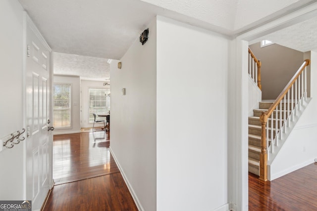 hall with stairway, baseboards, a textured ceiling, and hardwood / wood-style flooring