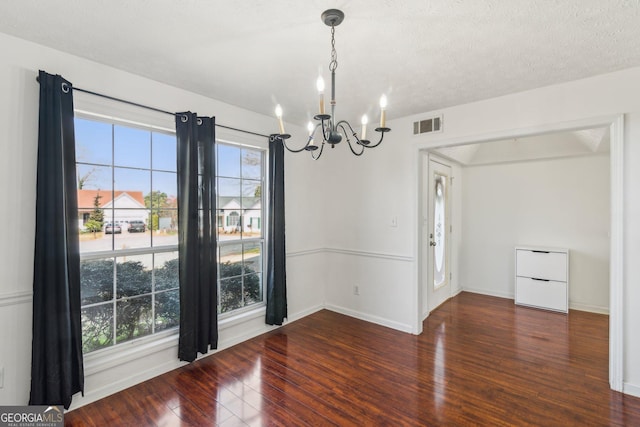 unfurnished room featuring visible vents, a notable chandelier, a healthy amount of sunlight, and hardwood / wood-style flooring