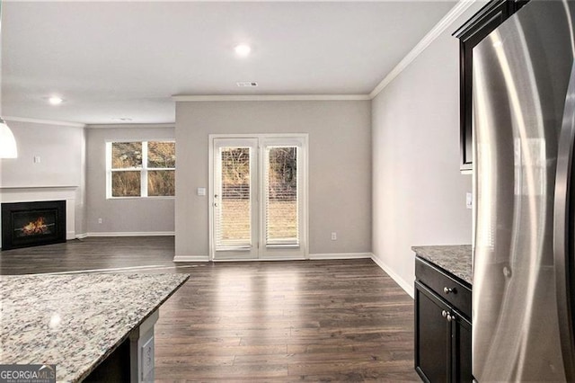 kitchen with dark wood-style flooring, a warm lit fireplace, freestanding refrigerator, and ornamental molding