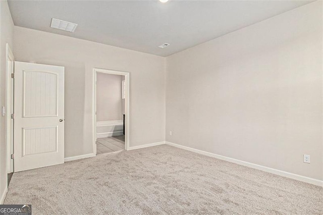 unfurnished bedroom with ensuite bath, carpet flooring, baseboards, and visible vents