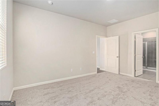 unfurnished bedroom featuring ensuite bath, baseboards, and carpet floors