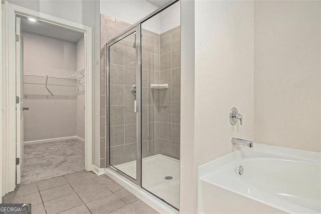 full bath featuring tile patterned flooring, a spacious closet, a bath, and a stall shower