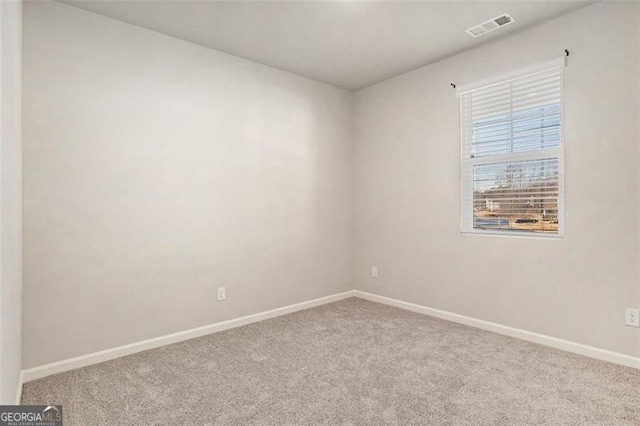 empty room with carpet, visible vents, and baseboards