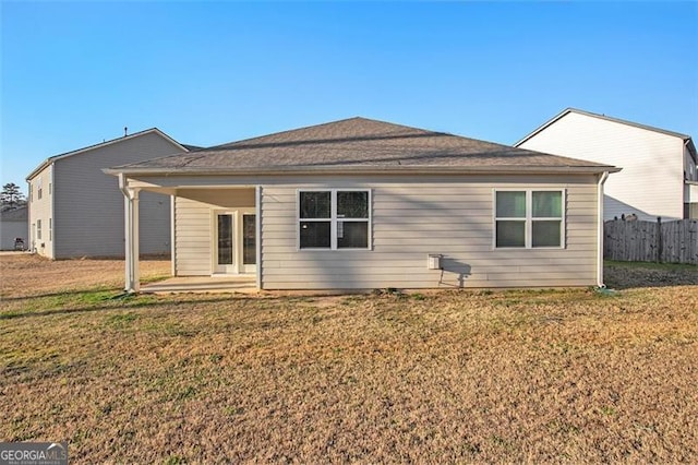 rear view of property featuring a yard, a patio area, and fence