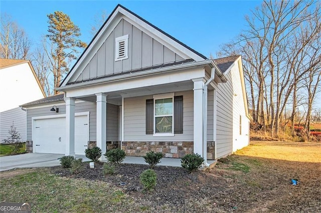 view of front of home with driveway, stone siding, covered porch, board and batten siding, and a garage