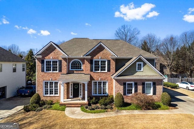 view of front of house with concrete driveway, fence, brick siding, and a shingled roof