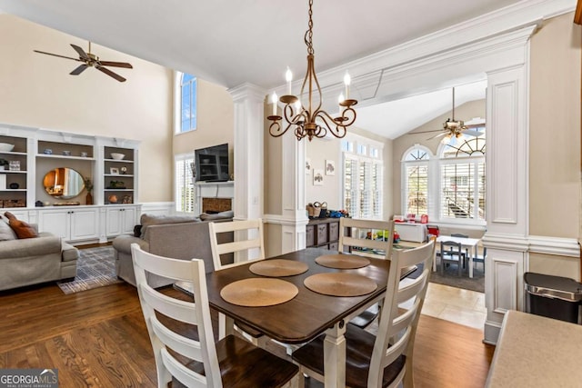 dining room featuring ceiling fan with notable chandelier, a healthy amount of sunlight, wood finished floors, and ornate columns