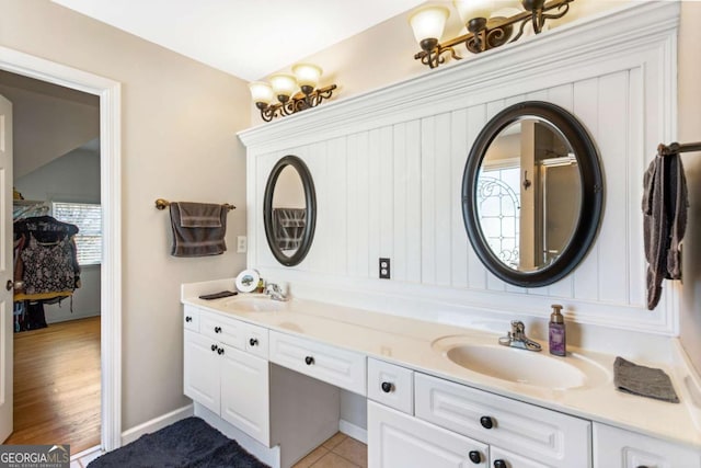 bathroom with double vanity, baseboards, and a sink