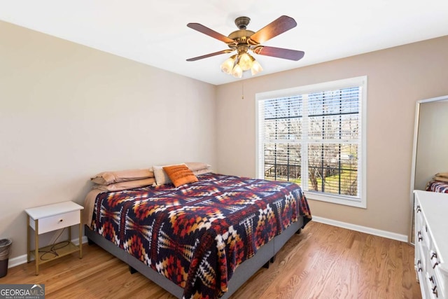 bedroom featuring a ceiling fan, light wood-type flooring, and baseboards