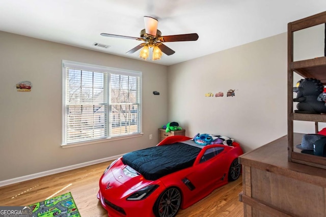 bedroom with ceiling fan, visible vents, baseboards, and wood finished floors