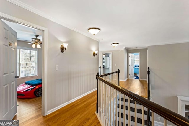 hall with an upstairs landing, light wood-style floors, and ornamental molding