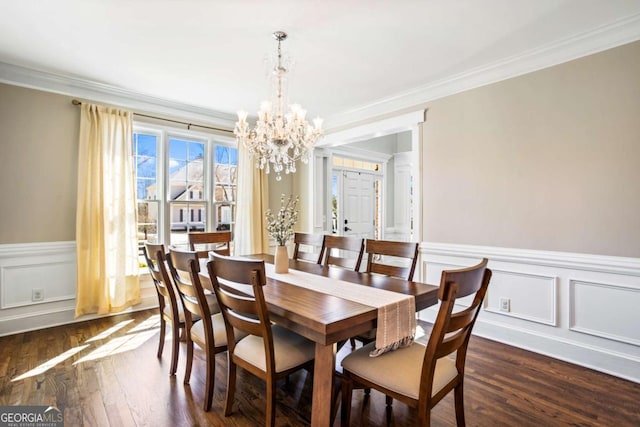 dining area featuring a wainscoted wall, an inviting chandelier, dark wood finished floors, and ornamental molding