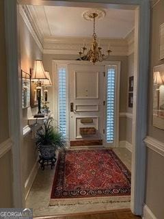 foyer with a notable chandelier, baseboards, and ornamental molding