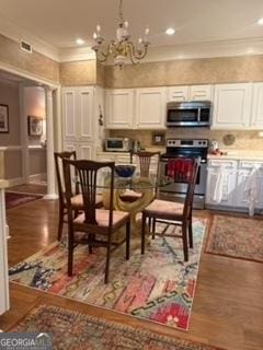 dining area featuring recessed lighting, wood finished floors, a chandelier, and ornamental molding