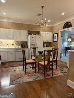 dining area with a notable chandelier, crown molding, and dark wood-type flooring