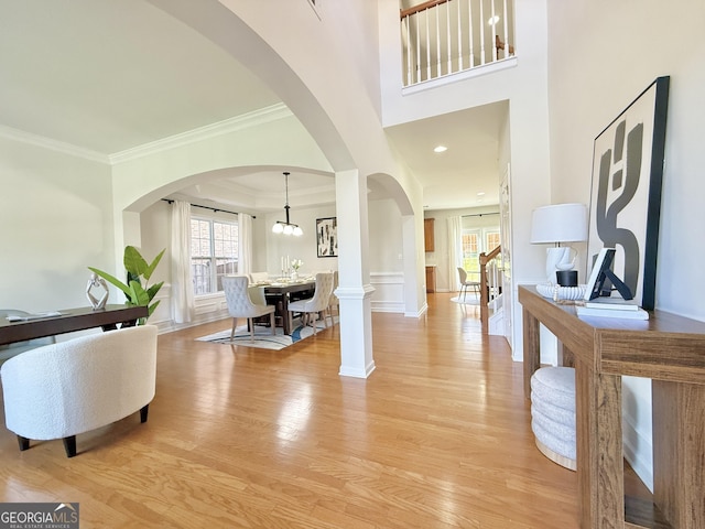 doorway featuring a wainscoted wall, visible vents, ornamental molding, wood finished floors, and a decorative wall