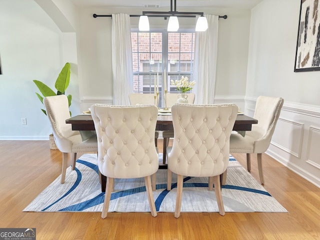 interior space with decorative columns, arched walkways, wood finished floors, and a decorative wall