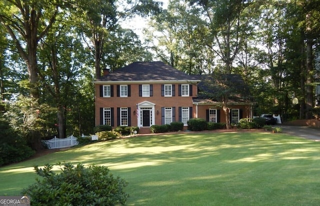 colonial home featuring a front yard and fence