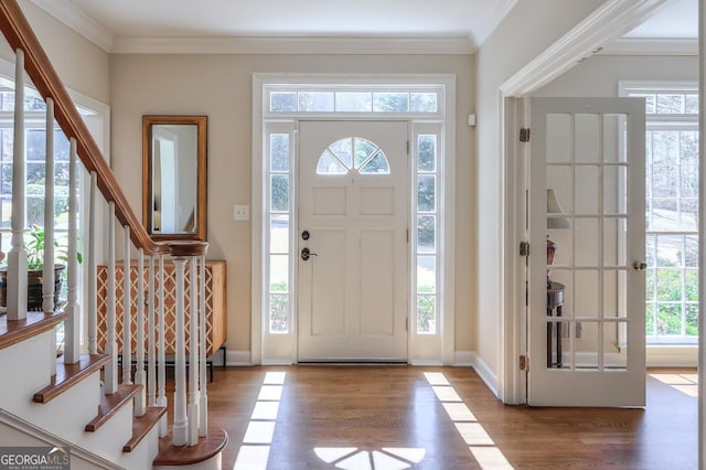 entryway featuring wood finished floors, stairs, baseboards, and ornamental molding