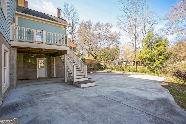 view of patio featuring a carport, a wooden deck, concrete driveway, and stairs