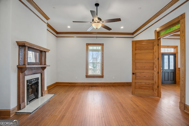 unfurnished living room featuring hardwood / wood-style floors, crown molding, a healthy amount of sunlight, and a fireplace