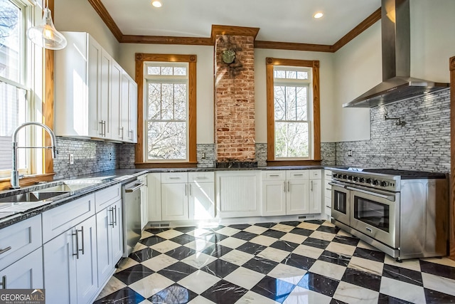 kitchen with a sink, white cabinetry, stainless steel appliances, wall chimney exhaust hood, and light floors