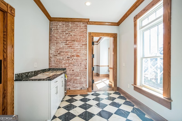 kitchen with ornamental molding, dark countertops, white cabinetry, baseboards, and light floors