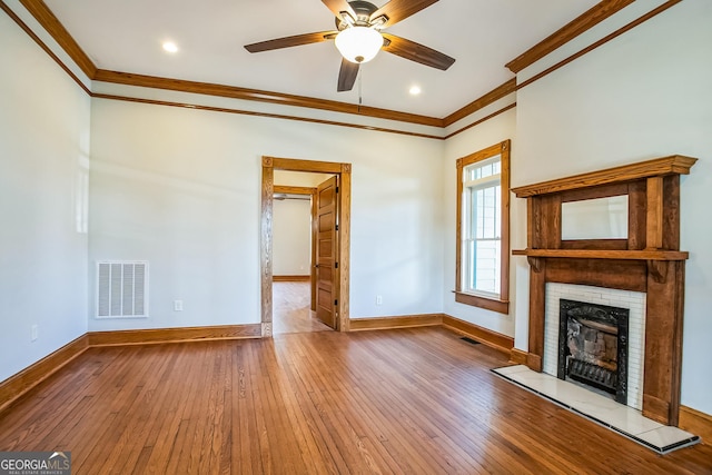 unfurnished living room featuring visible vents, a fireplace with raised hearth, baseboards, ornamental molding, and hardwood / wood-style flooring