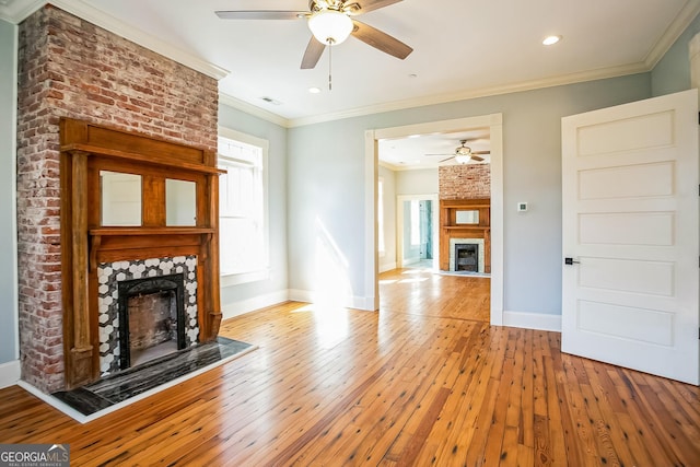 unfurnished living room with visible vents, crown molding, a large fireplace, baseboards, and hardwood / wood-style floors