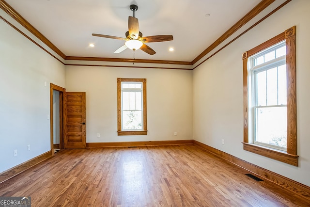 spare room with visible vents, ornamental molding, light wood-style floors, baseboards, and ceiling fan