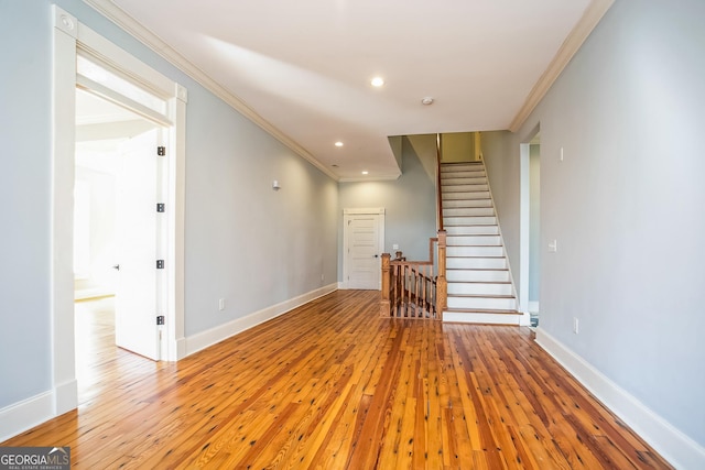 unfurnished living room with crown molding, baseboards, and wood-type flooring