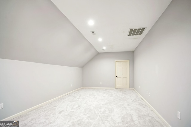 additional living space with vaulted ceiling, light colored carpet, visible vents, and baseboards