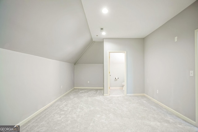 additional living space with lofted ceiling, light colored carpet, visible vents, and baseboards