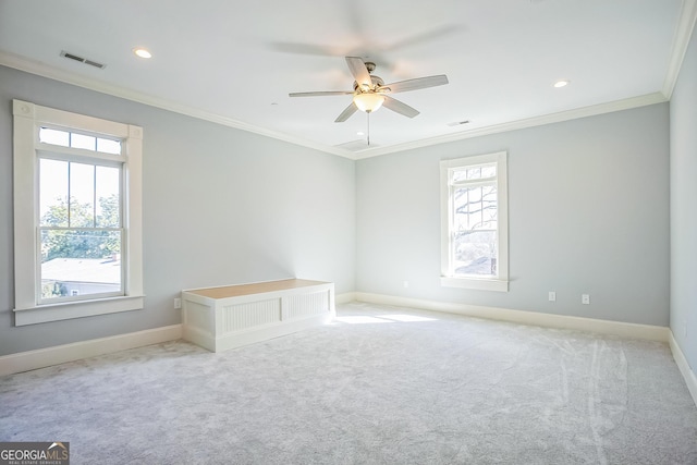 carpeted empty room featuring visible vents, a healthy amount of sunlight, crown molding, and baseboards