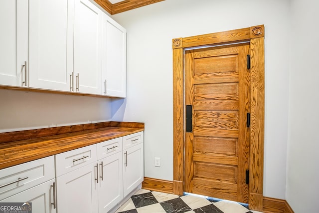 kitchen featuring tile patterned floors, white cabinets, baseboards, and butcher block countertops