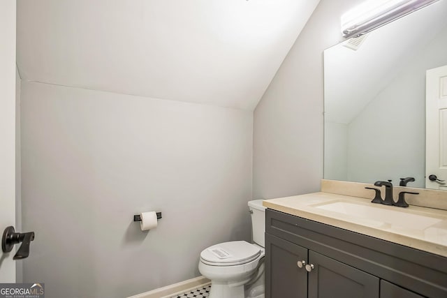 bathroom with baseboards, lofted ceiling, toilet, and vanity