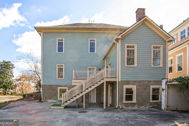 back of property featuring a wooden deck, stairway, and a chimney