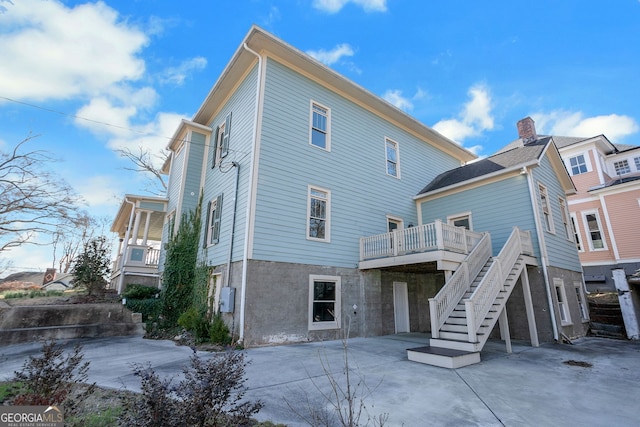 back of house featuring a wooden deck, a patio, and stairs