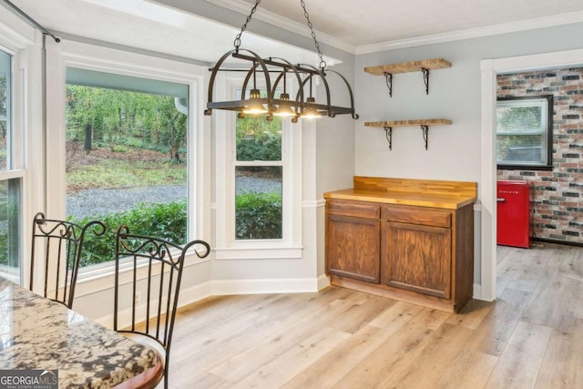 dining space with baseboards, ornamental molding, and light wood finished floors