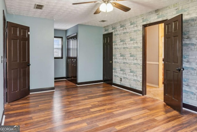 unfurnished bedroom with visible vents, baseboards, a textured ceiling, and wood finished floors