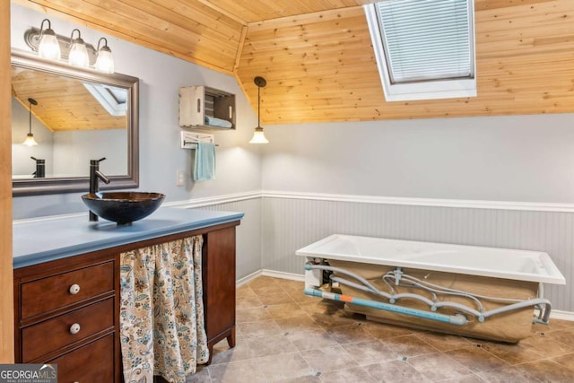 full bath featuring vanity, wooden ceiling, lofted ceiling with skylight, and wainscoting