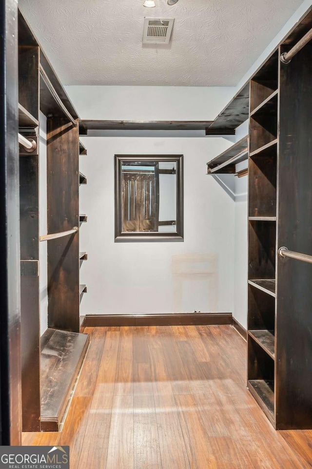 walk in closet featuring hardwood / wood-style flooring and visible vents