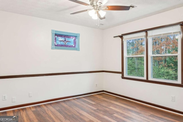 spare room with ceiling fan, baseboards, a textured ceiling, and wood finished floors