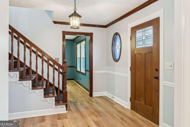 foyer entrance featuring stairs, baseboards, wood finished floors, and crown molding