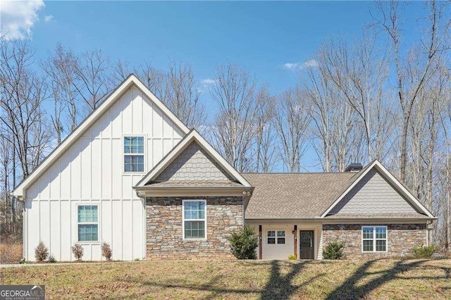 view of front of home with stone siding, board and batten siding, a chimney, and a front lawn